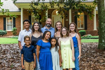 A large and blended and mixed happy family standing in front of their home