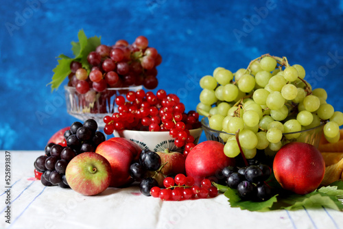 Colorful still life with seasonal berries on a table. Red currant  green grapes  nectarines and apples close up photo. Nutrition concept. 