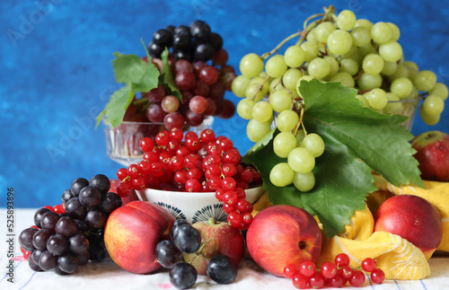 Colorful still life with seasonal berries on a table. Red currant  green grapes  nectarines and apples close up photo. Nutrition concept. 