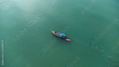 Aerial view from a drone of Thai traditional longtail fishing boats sailing in the sea. Top view of a fishing boat in the ocean.
