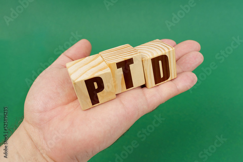 On a green background, in the hands of a person, cubes with the inscription - PTD photo