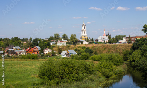 Panoramic top view of the city of Suzdal in Russia with historical architecture and a church among the lush green foliage of trees and a small river on a sunny summer day