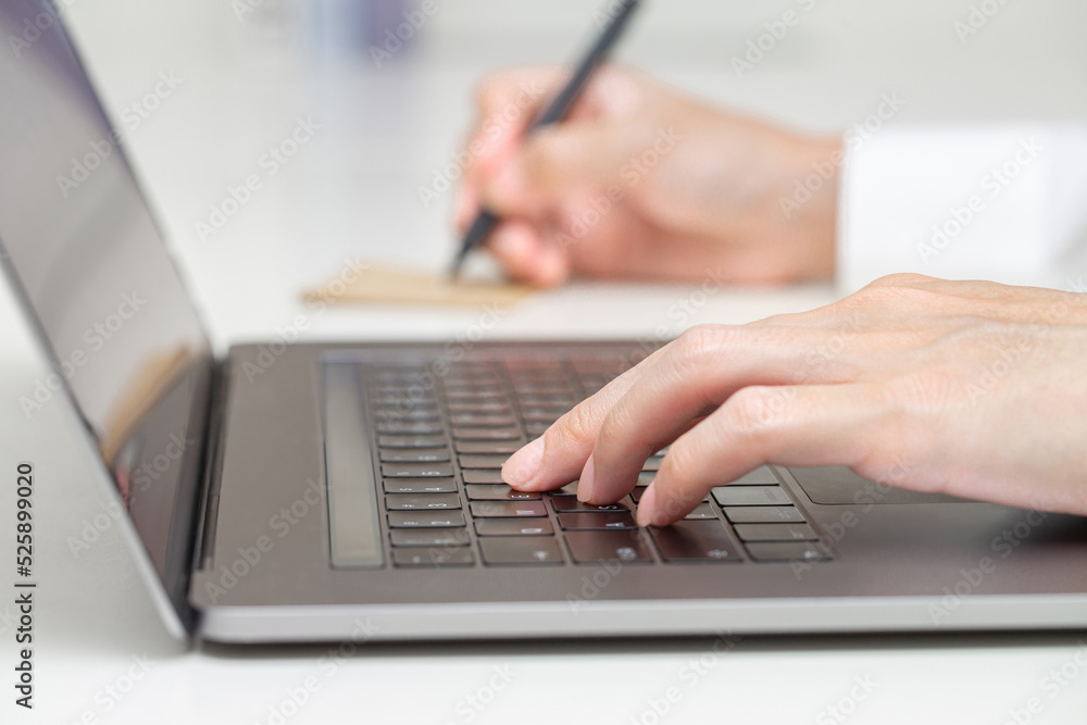 Close up shot of hand typing on laptop and taking note in business online meeting theme Close up shot of hand typing on laptop and taking note in business online meeting theme