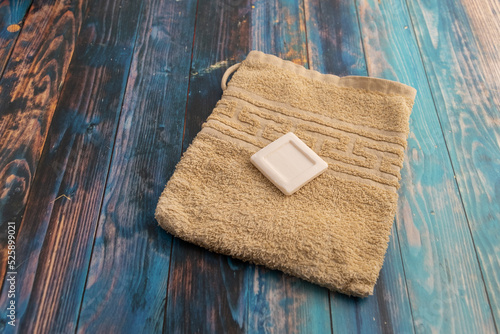 high angle view of a yellow washcloth with a piece of a white soap on a table photo
