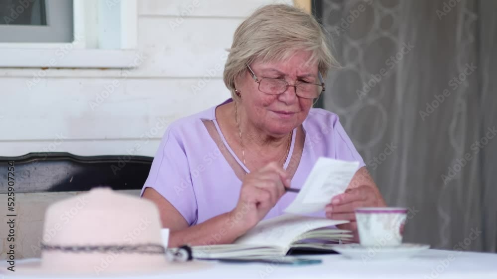 Adult senior woman calculating paper documents at home. Serious middle aged woman considers the family budget, pension costs. Adult senior woman calculating paper documents at home. Serious middle aged woman considers the family budget, pension costs.