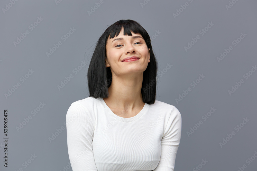 a happy woman stands on a dark background in a tight white T-shirt, slightly tilted her head back, calmly lowering her hands down a happy woman stands on a dark background in a tight white T-shirt, slightly tilted her head back, calmly lowering her hands down