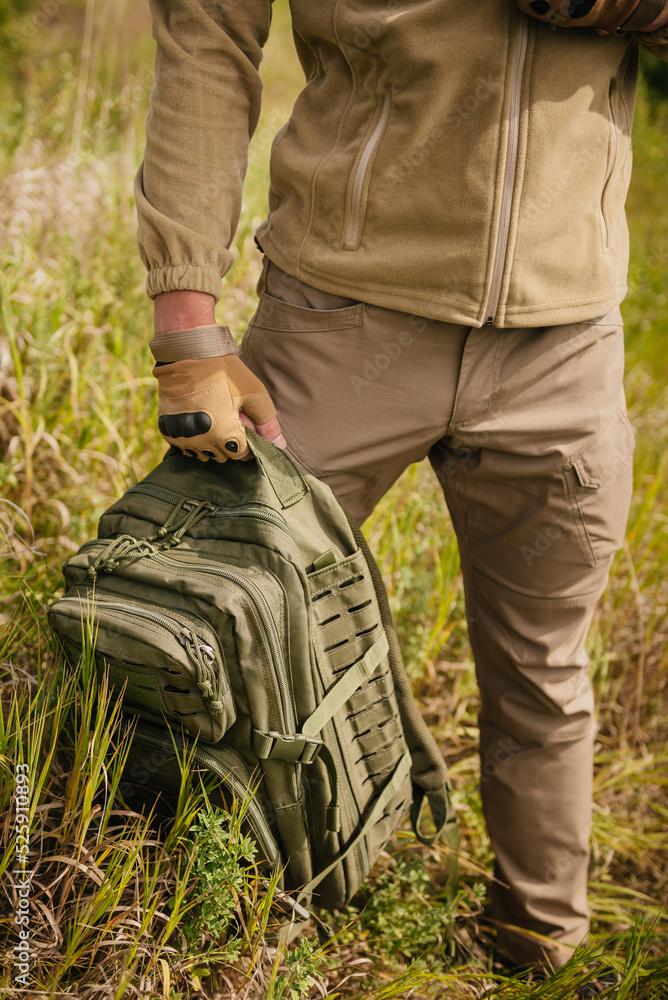 Hunting and camping clothes and equipment concept: unrecognizable man wears tactical hiking clothes and backpack
