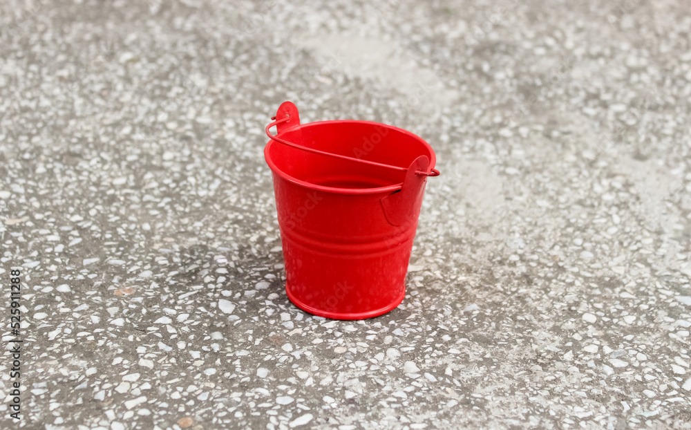 Small red metal bucket on the floor Small red metal bucket on the floor