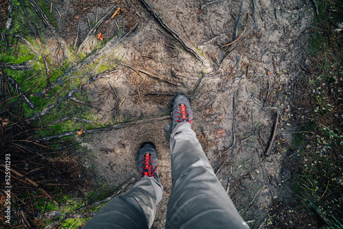 Top view of hiking shoes on a forest path. POV photo of hiking shoes on a dirt hiking trail.