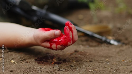 The hand of the slain infantryman falls to the ground covered in blood. The concept of watching a soldier in a war. Blood dripping from the hands of a soldier