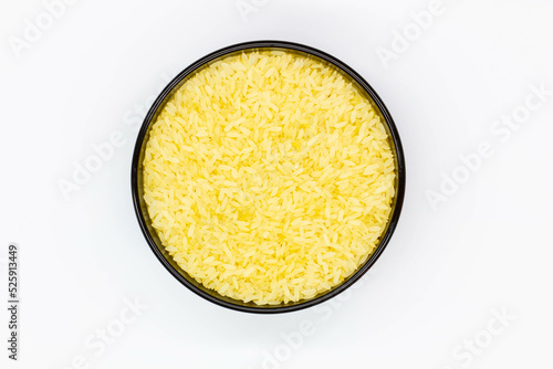 A plate of rice. Black bowl with grains of white rice on the white background. Healthy food. Raw white rice milled that has had husk, bran, germ removed. Isolated. Yellow grain. Top view. Close-up photo