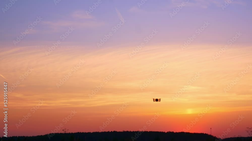 The drone takes off into the sunset sky over an unrecognizable place. A beautiful sky filled with sunset colors in which a drone flies with blinking lights. Four propellers lift the drone into the air The drone takes off into the sunset sky over an unrecognizable place. A beautiful sky filled with sunset colors in which a drone flies with blinking lights. Four propellers lift the drone into the air
