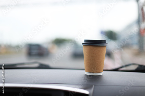 Cup of coffee on the windshield of a car. Travel by car. Quick breakfast in the car