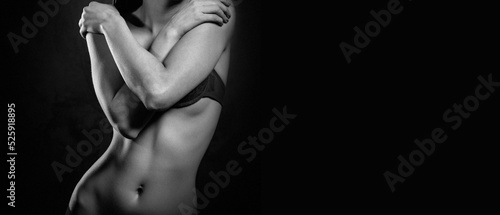 Sexy woman covers chest with hands posing on black background