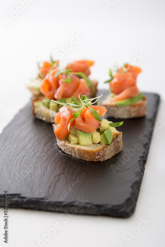 Salmon trout bruschetta on bread pieces with avocado and micro greens snack food