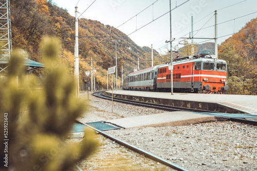 Passenger train with red locomotive rushing through the station of Trbovlje in early autumn. photo