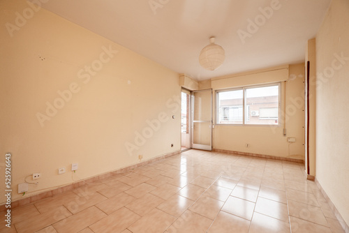 Empty room with pale pink painted walls and stoneware floors of the same color with windows and access to a terrace