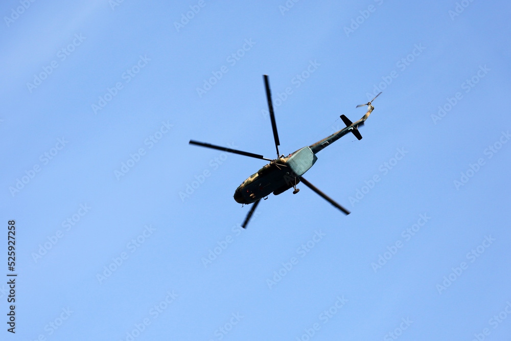 Russian military helicopter Mi-8 (NATO codification: Hip) in flight on blue sky background, bottom view Russian military helicopter Mi-8 (NATO codification: Hip) in flight on blue sky background, bottom view