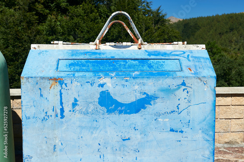 Fotografie old faded blue painted metal bin for collecting recyclable paper