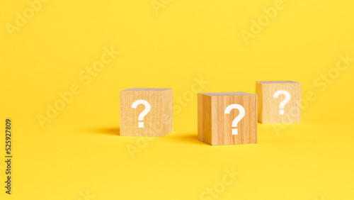front view on wood cubes with white question marks. many question arising concept, yellow background