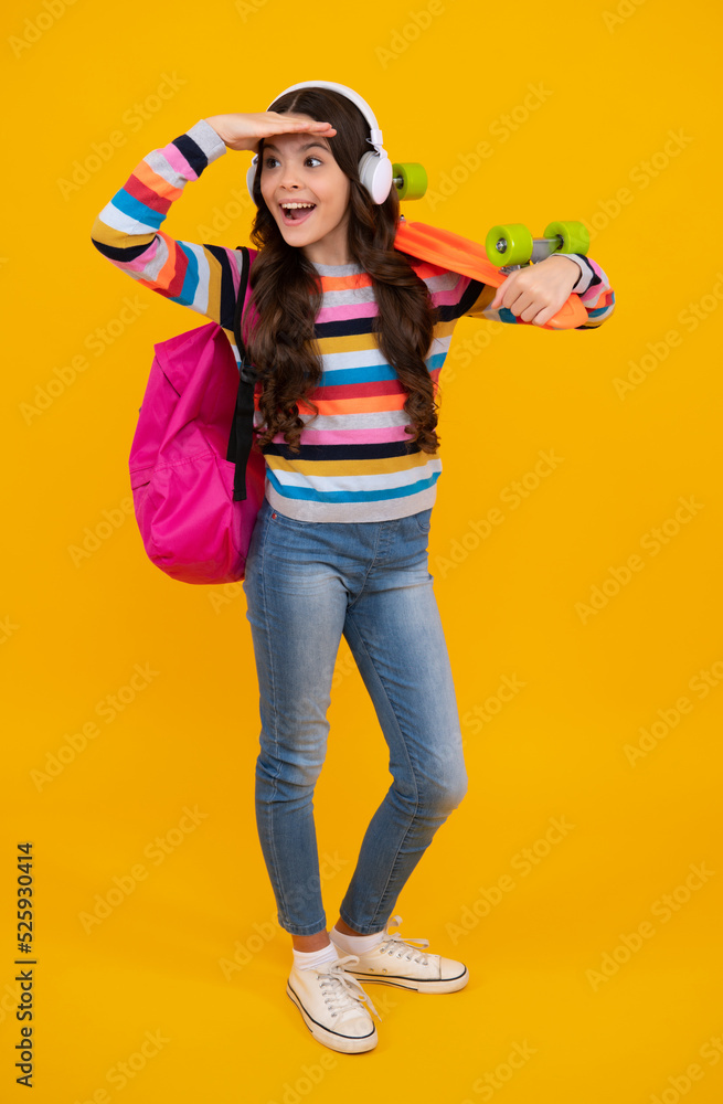 Teenagers lifestyle, casual youth culture. Teen girl with skateboard and headphone over isolated yellow studio background. Cool modern teenager in stylish clothes. Happy teenager. Teenagers lifestyle, casual youth culture. Teen girl with skateboard and headphone over isolated yellow studio background. Cool modern teenager in stylish clothes. Happy teenager.