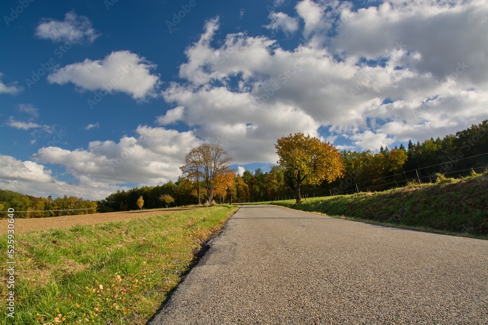 Fototapeta premium A road in a landscape with an arch full of clouds