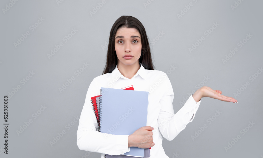Teen girl with notebooks standing over gray background with copy space. Educational concept for school. Portrait of young student. Stop school bullying or harassment. Teen girl with notebooks standing over gray background with copy space. Educational concept for school. Portrait of young student. Stop school bullying or harassment.
