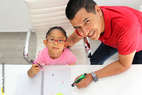 Latino dad and daughter, teacher and student draw in a notebook with colors in this back to school to improve skills with Autism Spectrum Disorder (ASD)