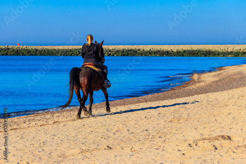 Young woman riding horse in sand beach of the Baltic sea in Darlowko, Poland