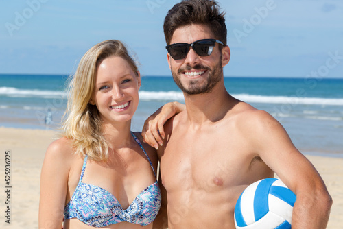 happy active man and woman playing volleyball on beach together