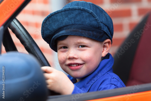 Big Dream of a Little Boy / Cute little rascal child sitting in dads car on steering wheel and plays driving