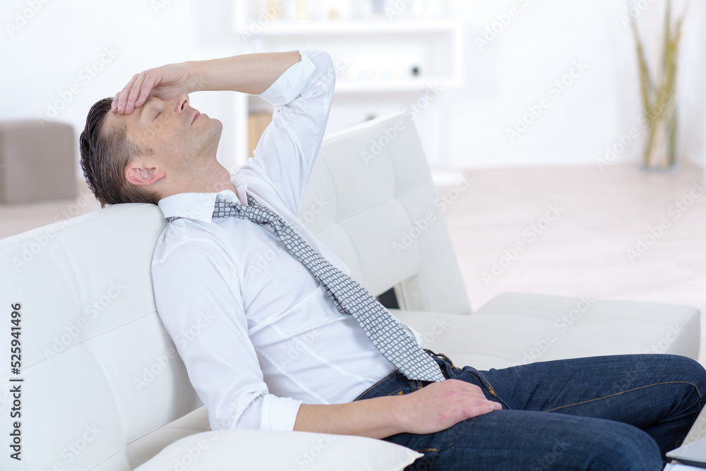businessman leaning back on sofa holding his head businessman leaning back on sofa holding his head