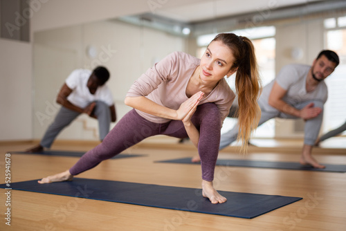 Multiethnic group of people exercising yoga poses in gym.