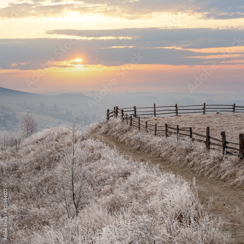 Winter coming. Last days of autumn  morning in mountain countryside peaceful picturesque hoarfrosted scene. Dirty road from hills to the village. Ukraine  Carpathian mountains.