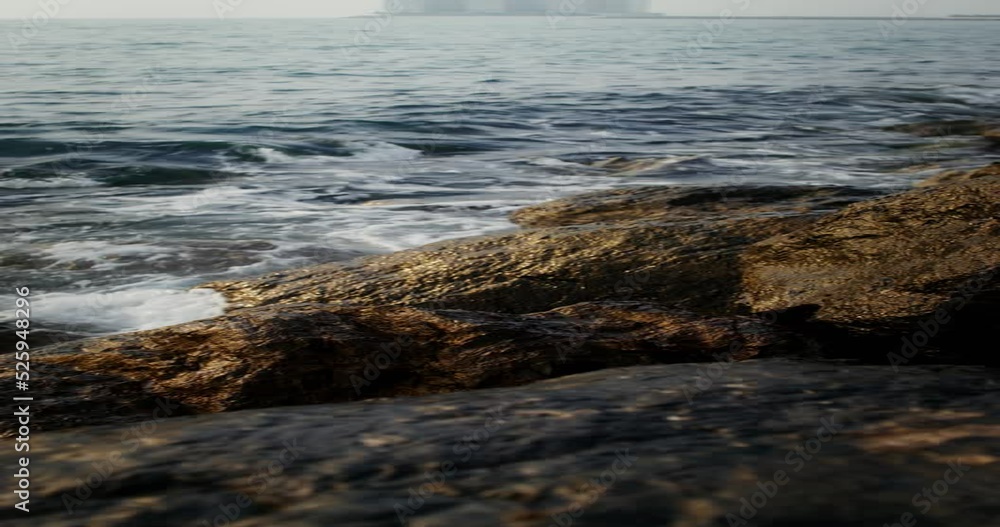 Sea waves hit large rocks on the coast, foaming and splashing as they wash over the boulders. The hotel complex is visible on the peninsula in the distance, vertical video. 4k video, red komodo Sea waves hit large rocks on the coast, foaming and splashing as they wash over the boulders. The hotel complex is visible on the peninsula in the distance, vertical video. 4k video, red komodo