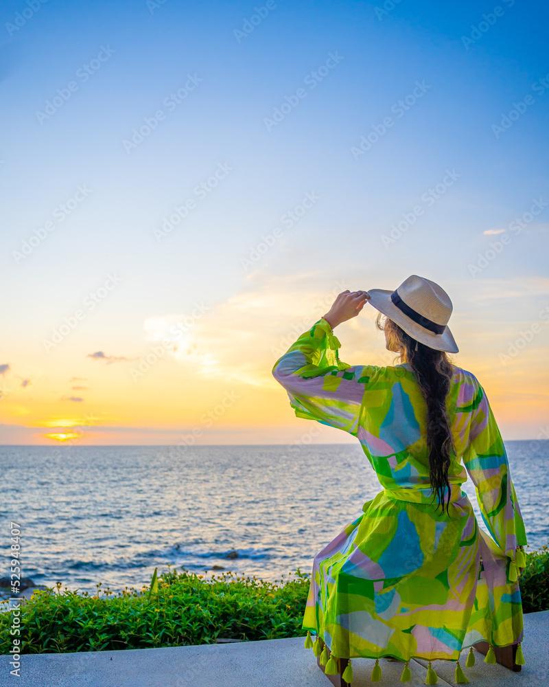 Lady with. a hat looking at the sunset in the ocean