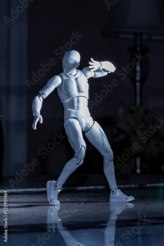 Standing male figurine raising arm blocking bright light from face.