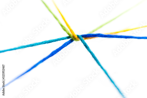 Yellow, green, blue, teal, yarn intertwined and radiating outward on a white background. photo