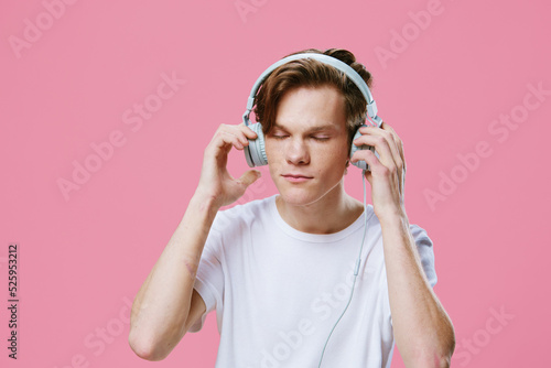 portrait of a guy in a white T-shirt putting on bright headphones to listen to music