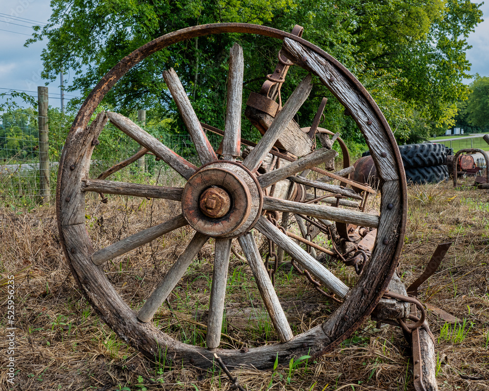 Weathered old cracked and rusted wooden spoked wagon wheel. Weathered old cracked and rusted wooden spoked wagon wheel.