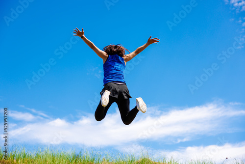 スポーツウエアを着て土手でジャンプする女性