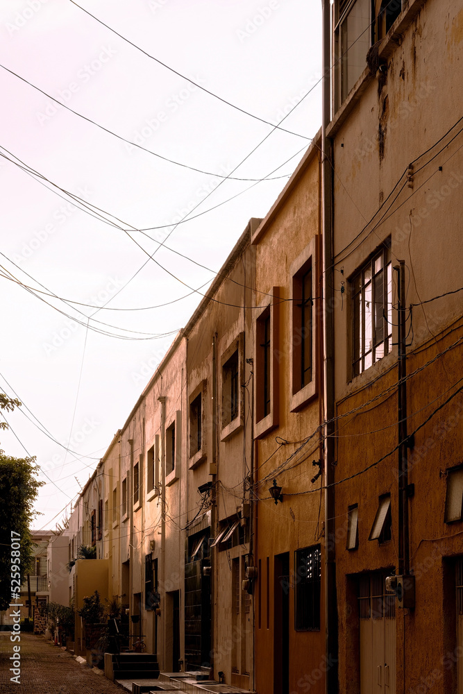 adjoining yellow and mustard-colored houses, at sunset after a rain, wet walls and floors, windows and wires adjoining yellow and mustard-colored houses, at sunset after a rain, wet walls and floors, windows and wires