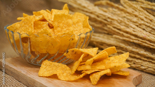 Selicious nachos chips in glass bowl on a cutting board, isolated on burlap background