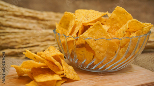 Selicious nachos chips in glass bowl on a cutting board, isolated on burlap background