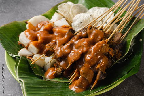 sate padang, indonesian cuisine padang beef, intestine satay with spicy peanut sauce and rice cake, photo