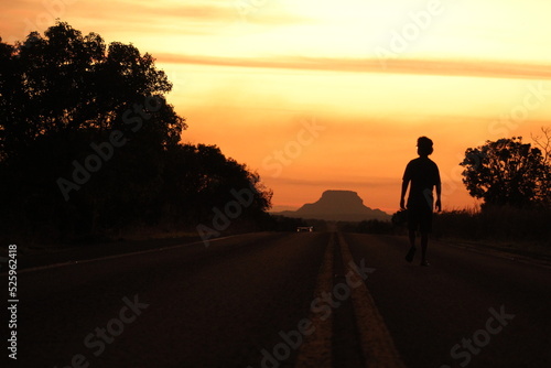 Silhueta de homem no por do sol na BR-230 (Transamazônica) em Riachão, Maranhão, com morro da Chapada das mesas ao fundo