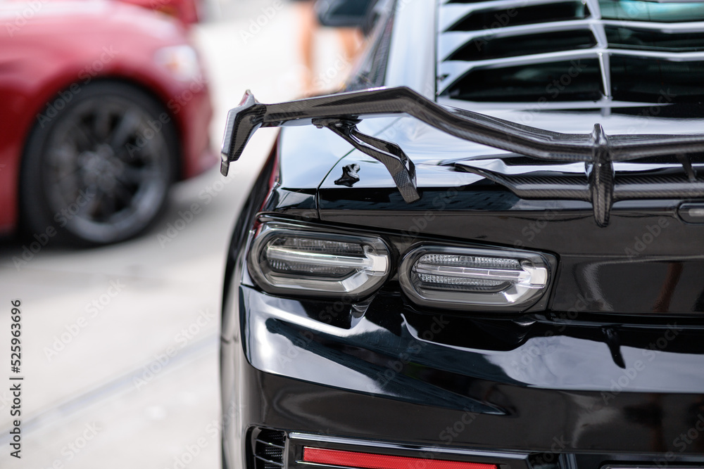 Luxury black sports car fragment, rear aerodynamics carbon spoiler and rear lights - obrazy, fototapety, plakaty 