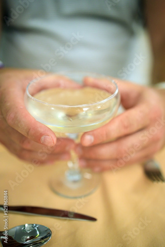 glass with champagne cocktail in male hands, close-up in blur