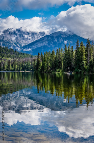 Reflections on Pyramid Lake in Jasper National Park with canoes nestled in the trees in the background 
