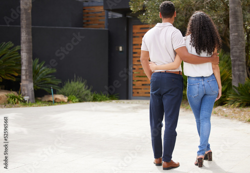 Property, real estate and new home with a man and woman homeowner looking at their house together outside. Property, real estate and an investment in their future with a couple standing on a driveway photo
